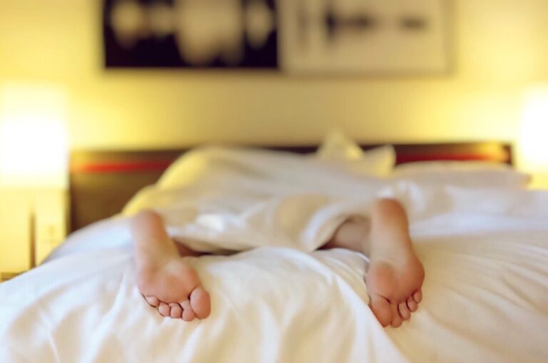 Pieds dépassant d’un lit défait, illustration de la fatigue chronique au réveil