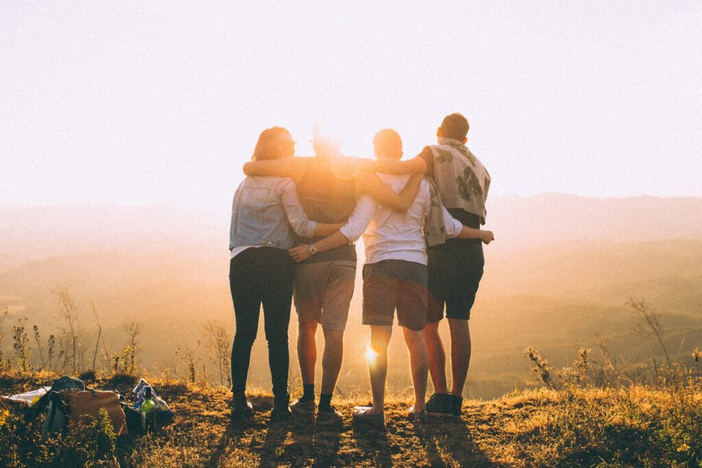 Groupe de personnes enlacées face au coucher du soleil, illustration des ateliers collectifs