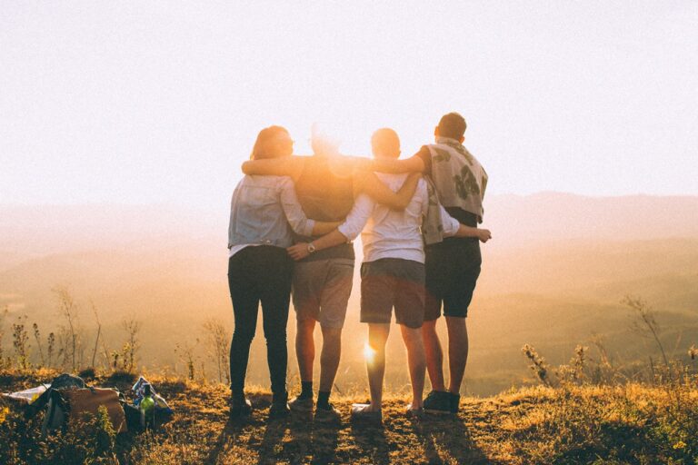 Groupe de personnes enlacées face au coucher du soleil, illustration des ateliers collectifs