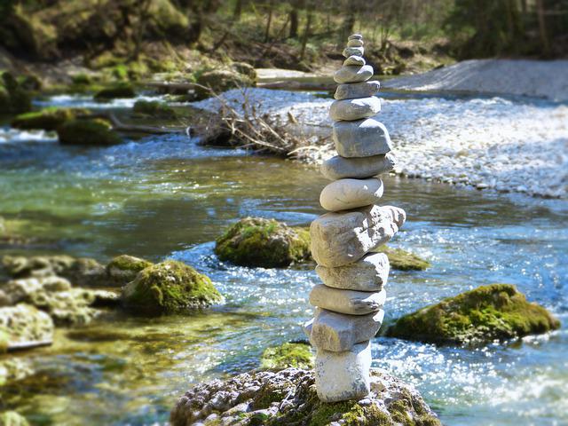 Cairn de galets en équilibre au milieu d’une rivière, illustration des stages de jeûne et détox
